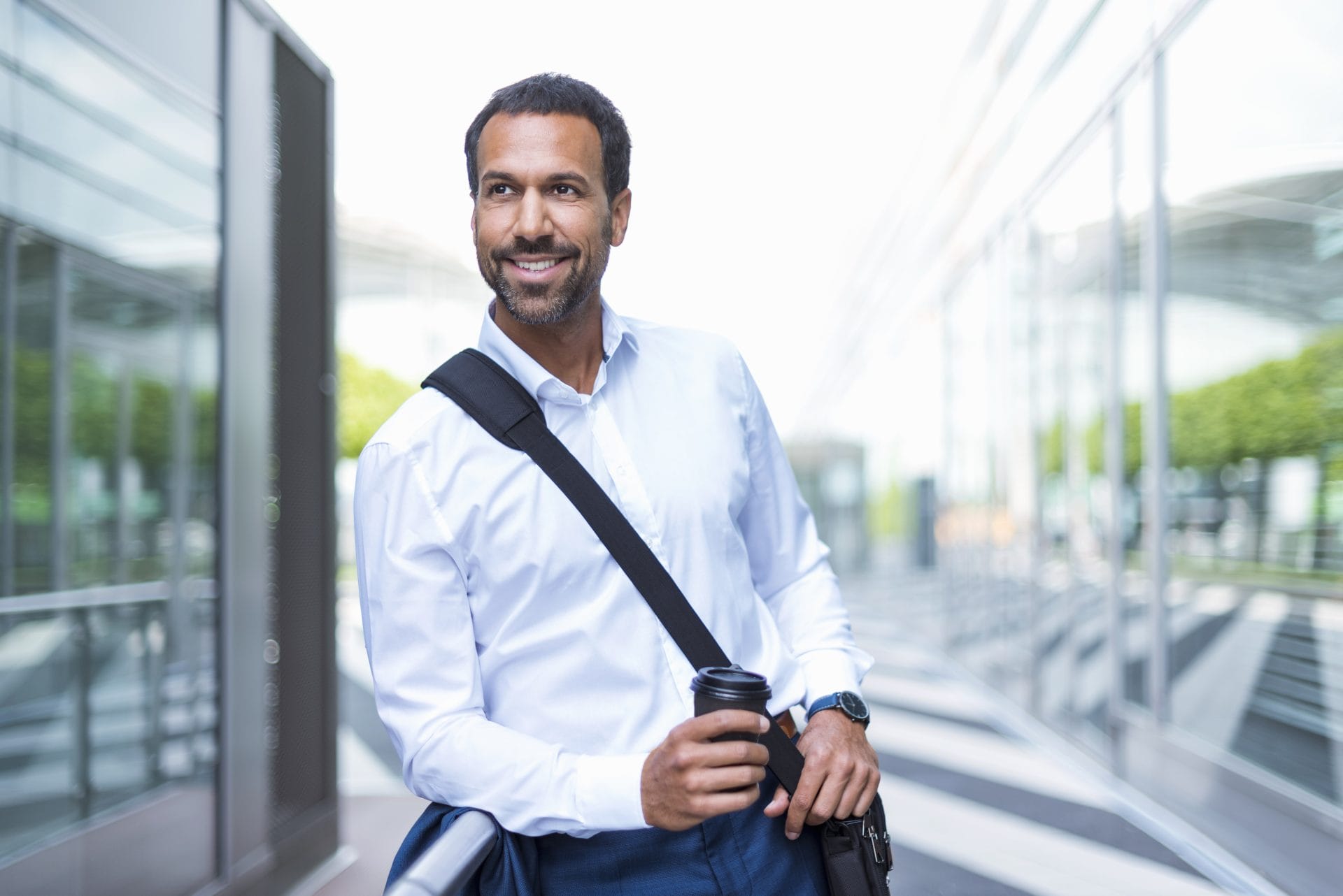 Smiling professional man carrying a shoulder bag, symbolizing confidence and career growth through skill-building and training opportunities.