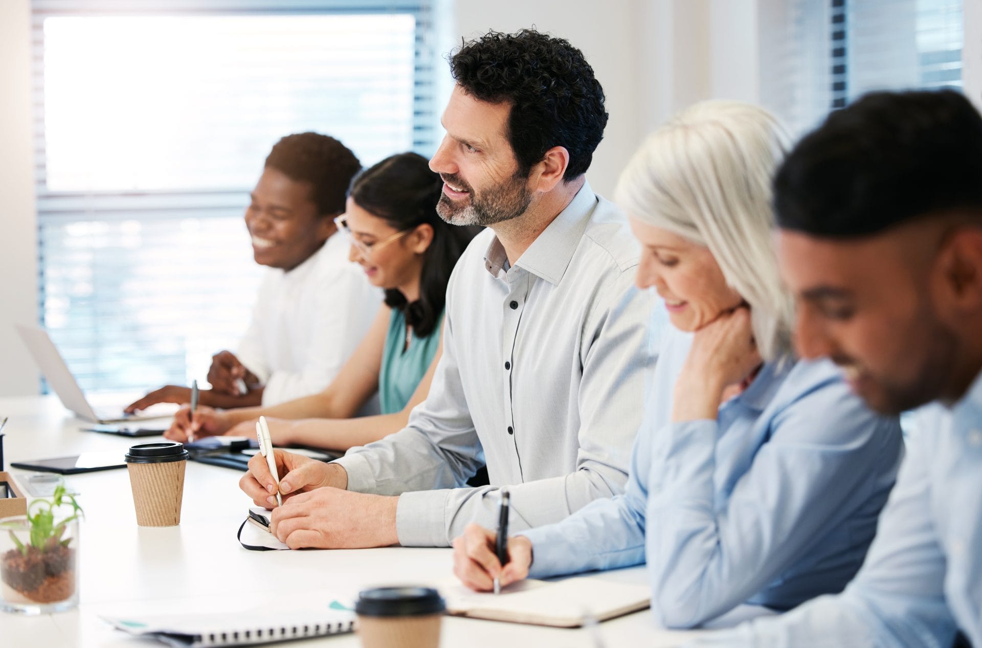 Group of professionals smiling and taking notes during a training session, representing collaboration between workforce partners.