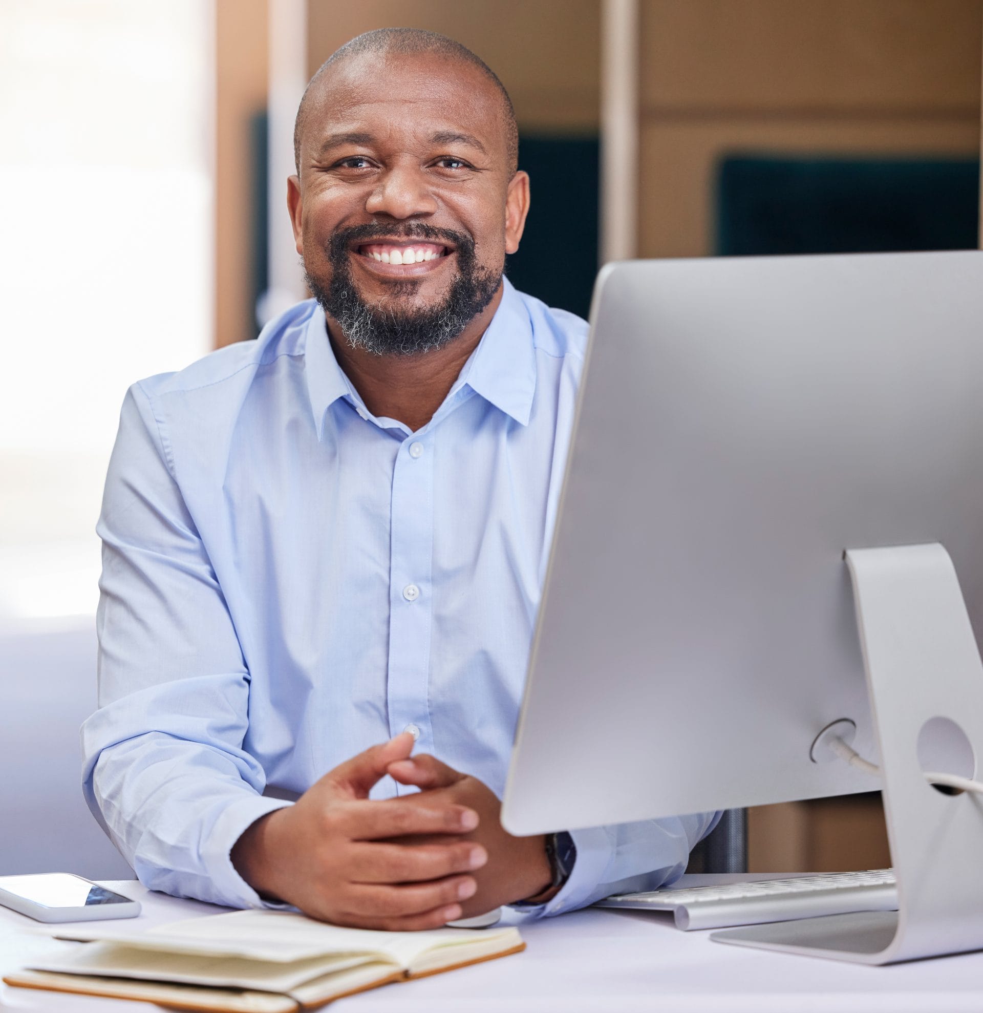 Smiling professional sitting at a desk in front of a computer, representing support and access to provider resources