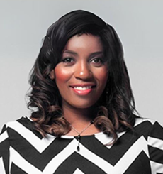 Professional headshot of a woman with dark hair wearing a black-and-white chevron-patterned top, smiling against a light background.