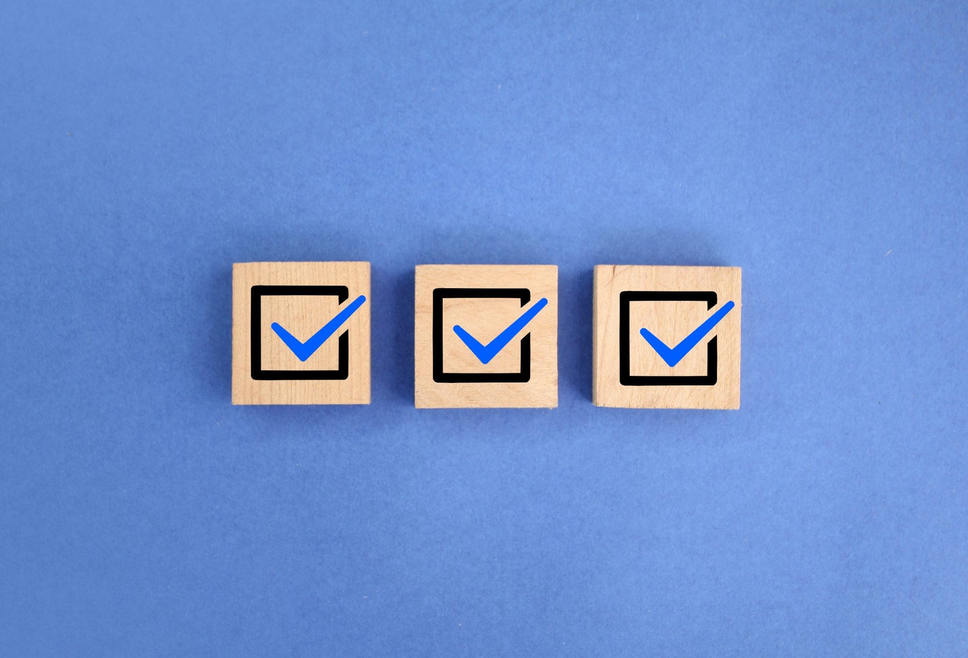 Three wooden blocks with blue checkmarks on a blue background, symbolizing tailored training solutions and completion.