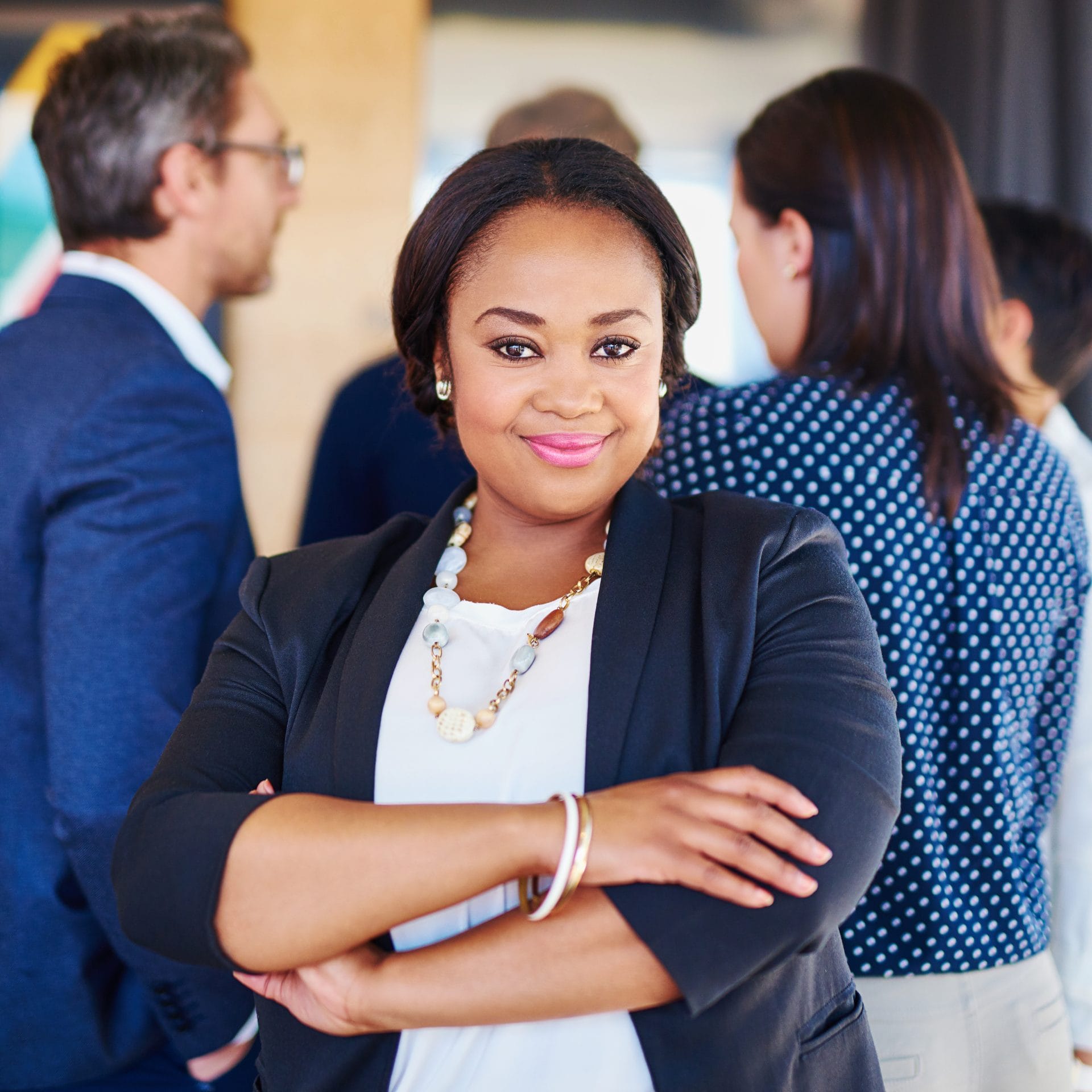 Confident woman standing with folded arms in a business setting, representing career advancement and leadership.