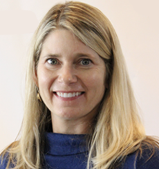 Professional headshot of a woman with blonde hair wearing a navy blue top, smiling against a neutral background.