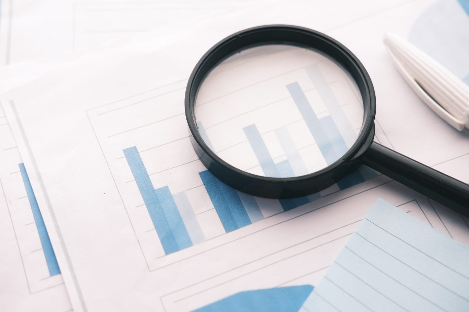 Magnifying glass resting on a financial chart, representing clarity, transparency, and accountability.
