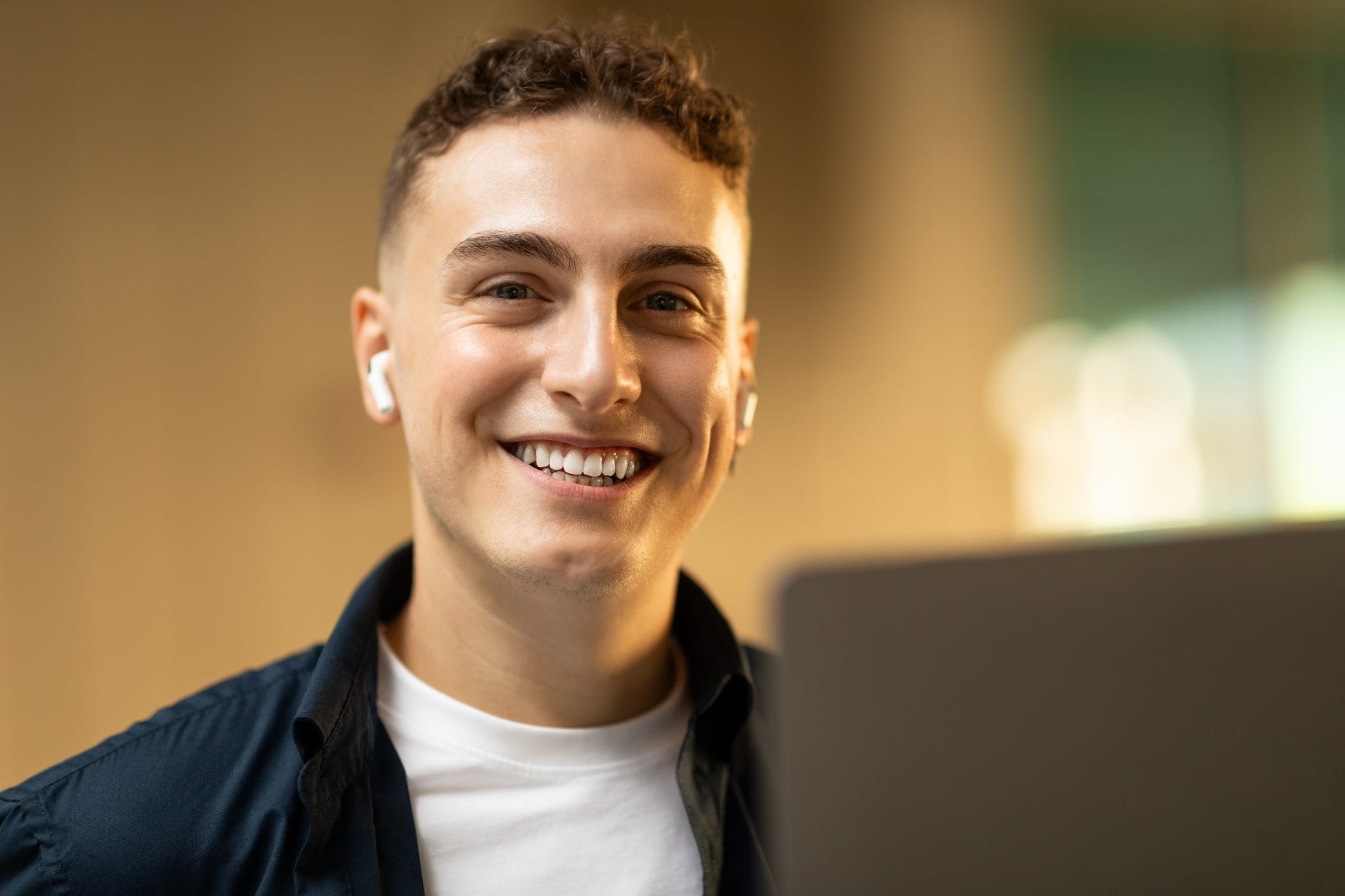 Young adult smiling while working on a laptop, reflecting enthusiasm and opportunity for youth career development.