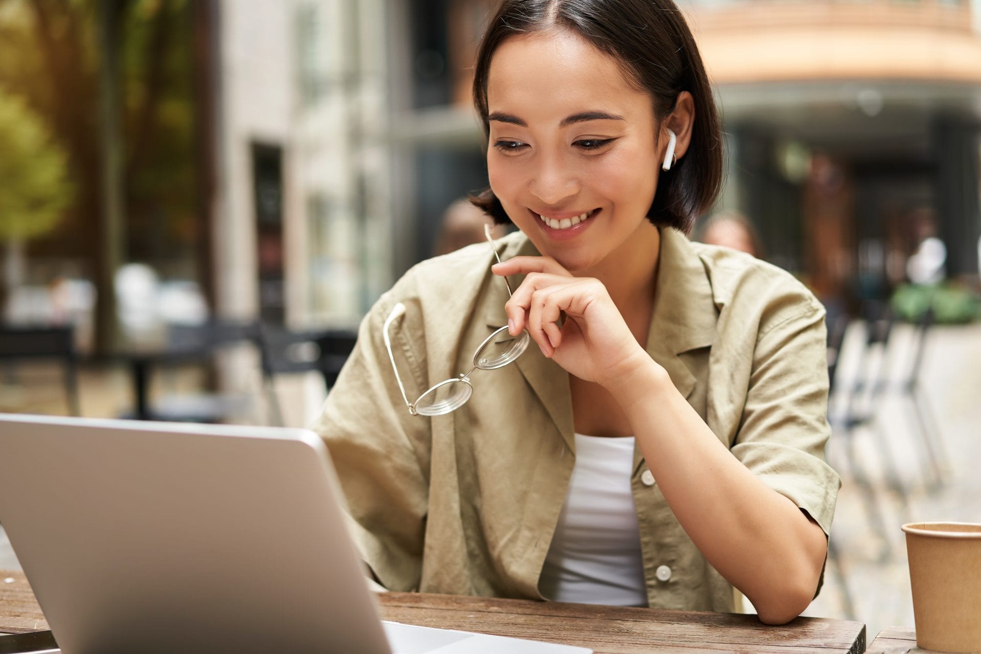 Smiling woman using a laptop with earbuds in, representing exploration of apprenticeship opportunities online.