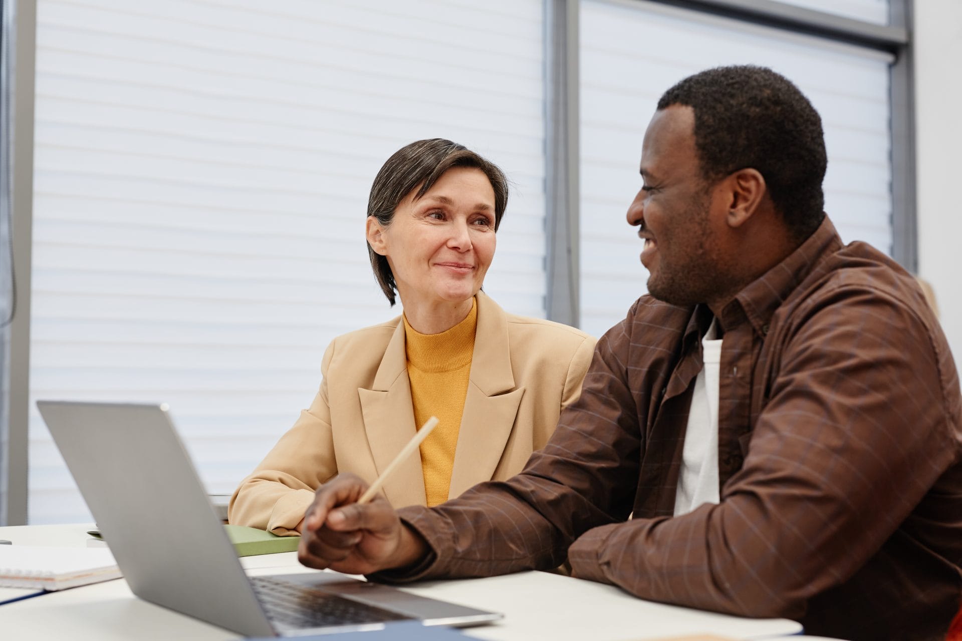 Man and woman talking across a desk in a professional setting, symbolizing inclusive career support and opportunity.