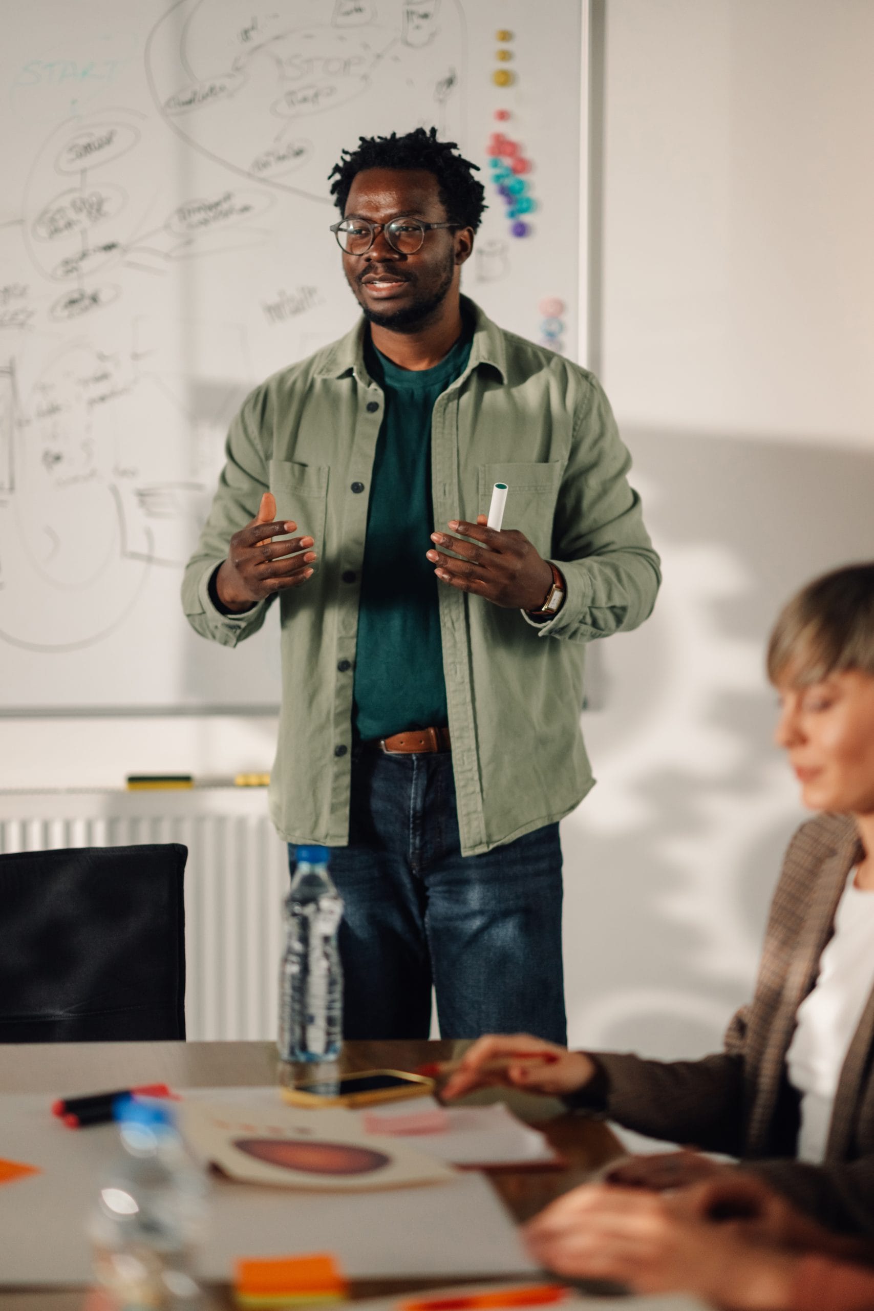 Professional instructor speaking in front of a whiteboard with colorful notes, representing a training provider guiding learners.