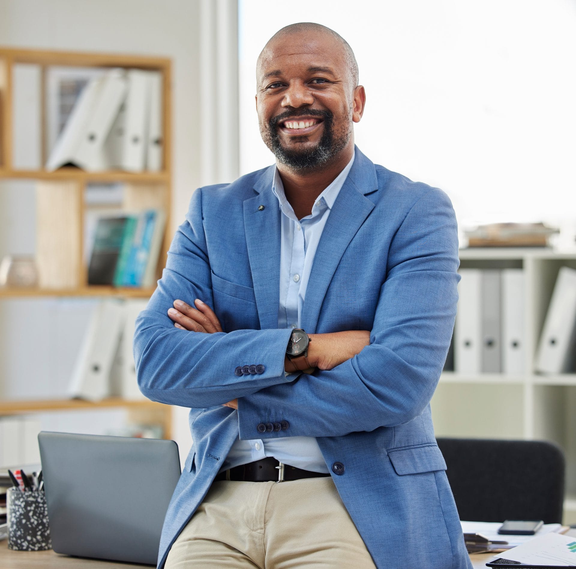 Confident professional man standing with arms crossed and smiling in an office, representing a positive path to reemployment through the RESEA Virtual Center.