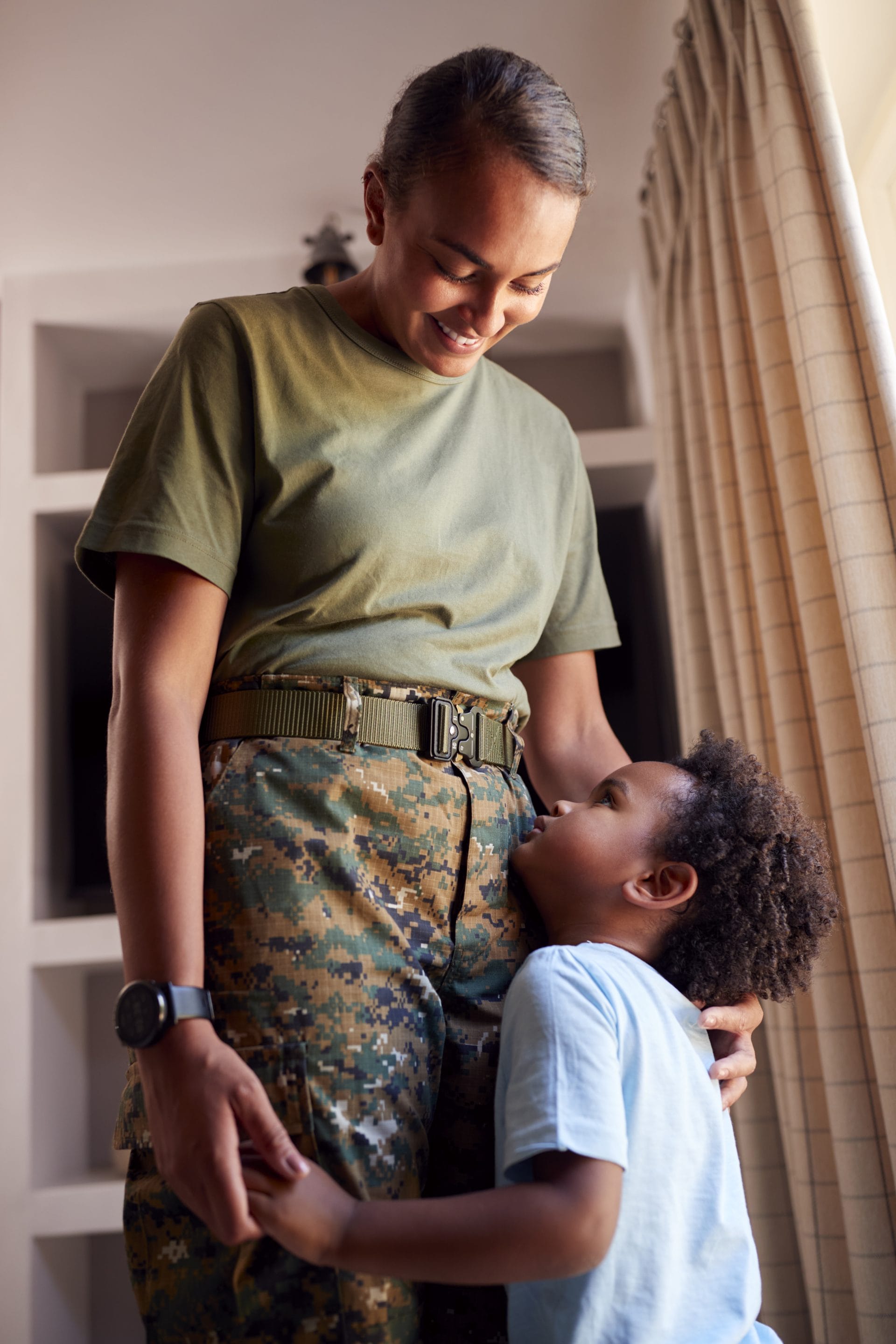 Military service member smiling while holding hands with a young child, symbolizing family, service, and career support.