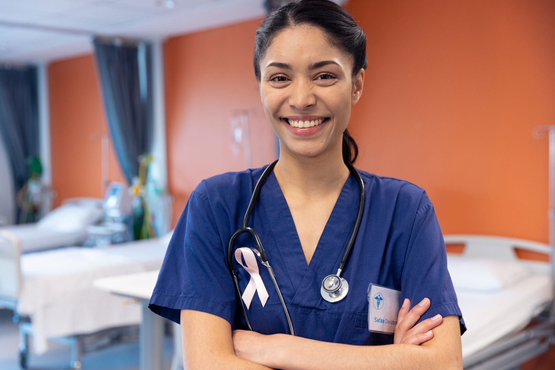 Smiling healthcare professional wearing scrubs and a ribbon pin, representing achievement and opportunity through training.