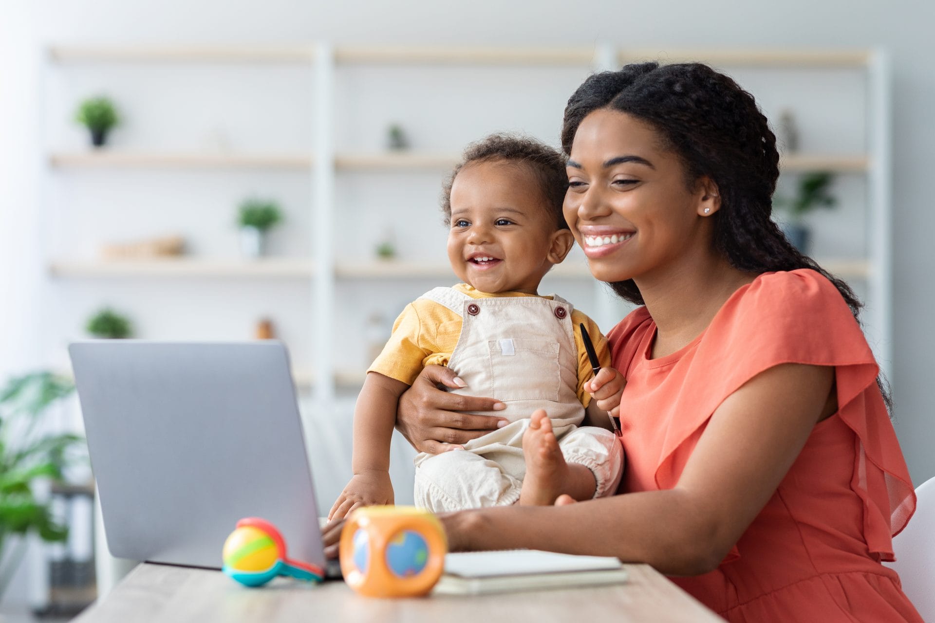 Smiling mother holding her young child at home, representing family stability and the transition from assistance to opportunity through the Welfare Transition Virtual Center.