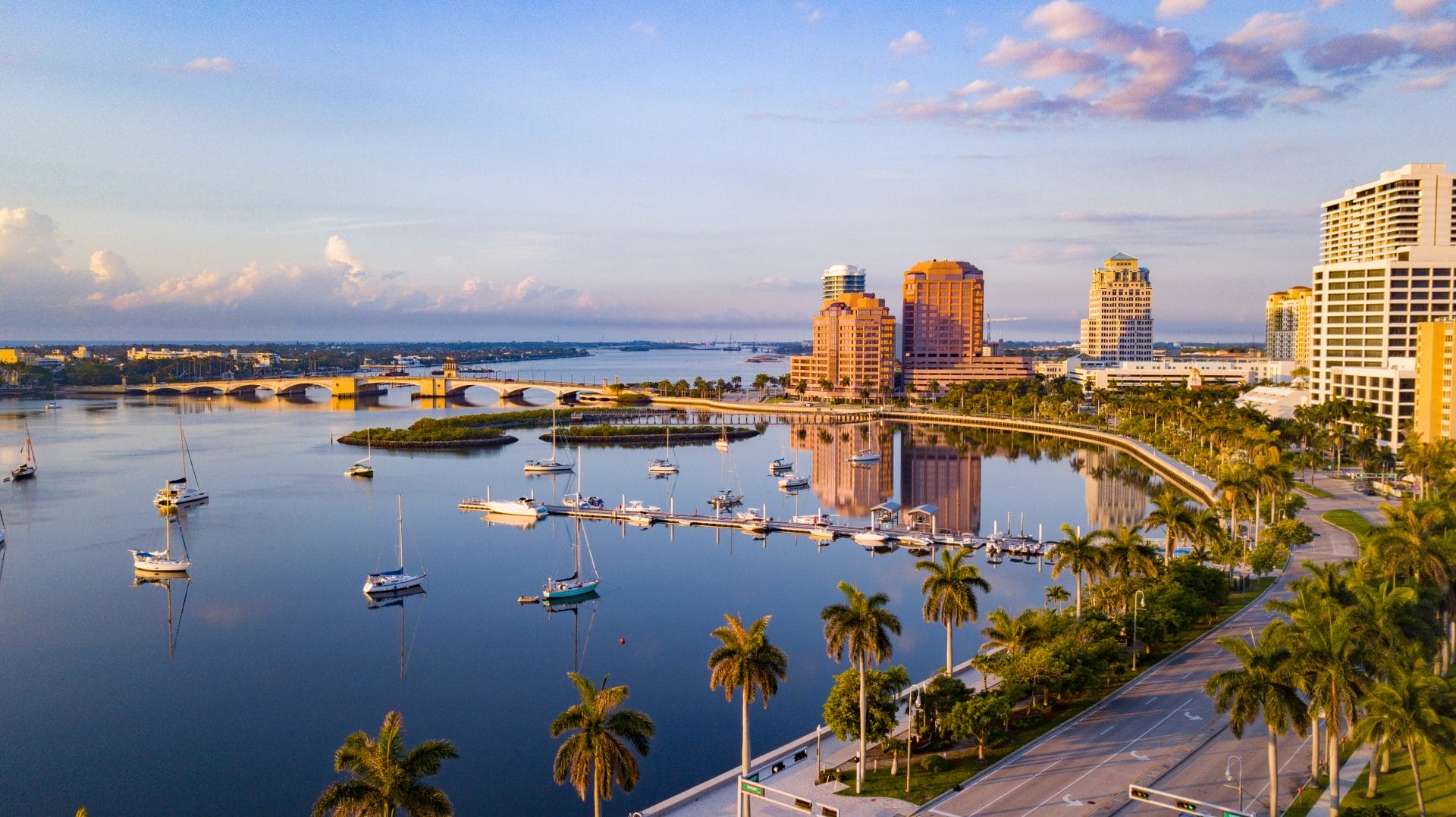 Cityscape of downtown West Palm Beach with waterfront buildings and palm trees, representing connection between education and industry.