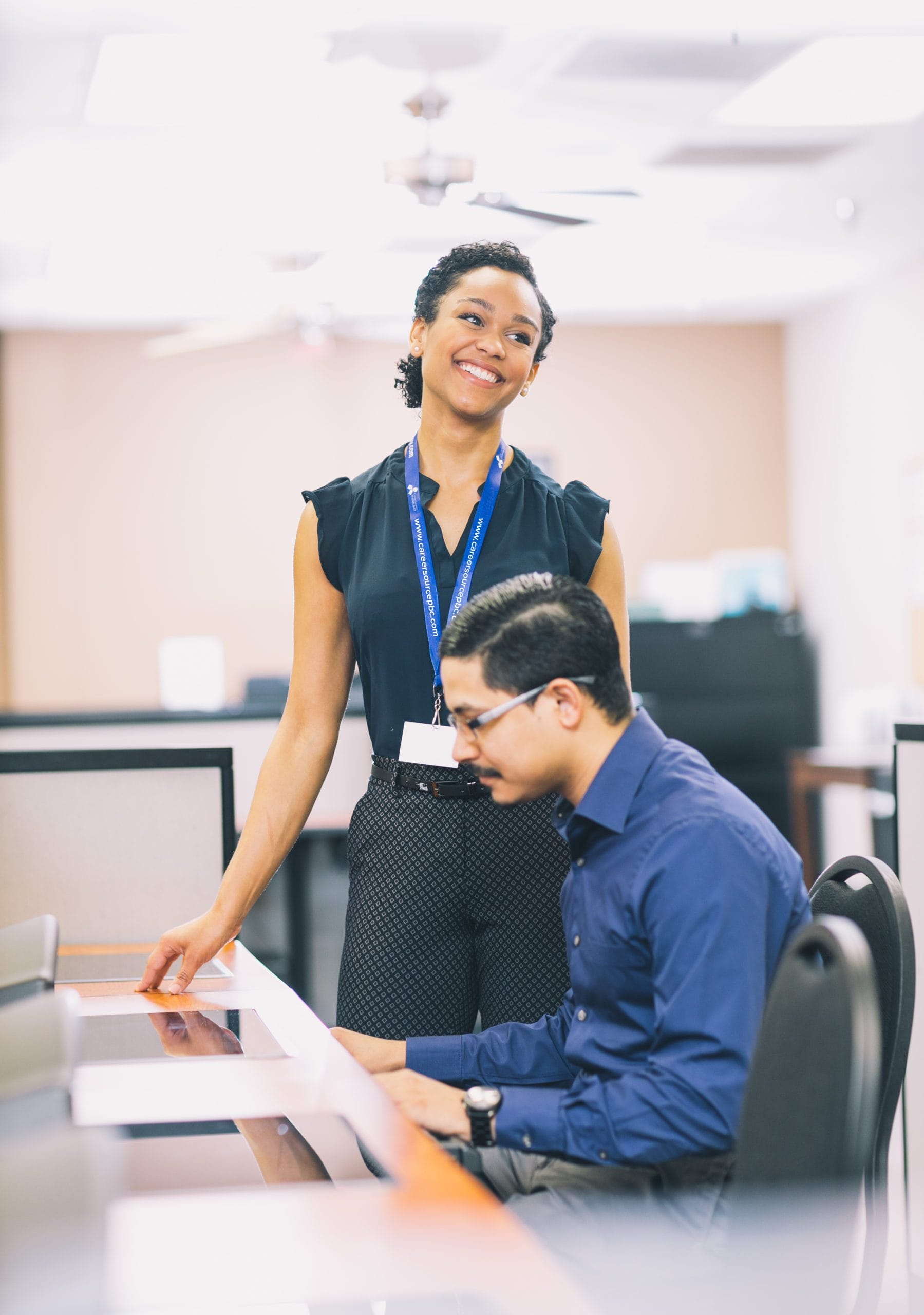 Friendly career center staff member assisting a customer at a computer, representing in-person support and welcoming service.