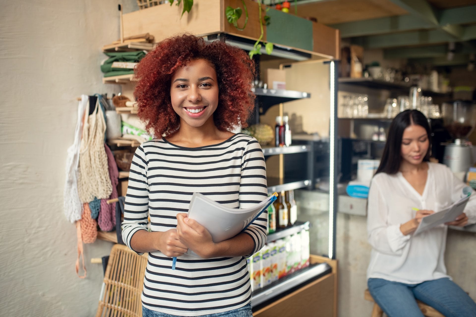 Smiling woman holding a clipboard in a small business setting, representing veteran transition and workforce partnerships.