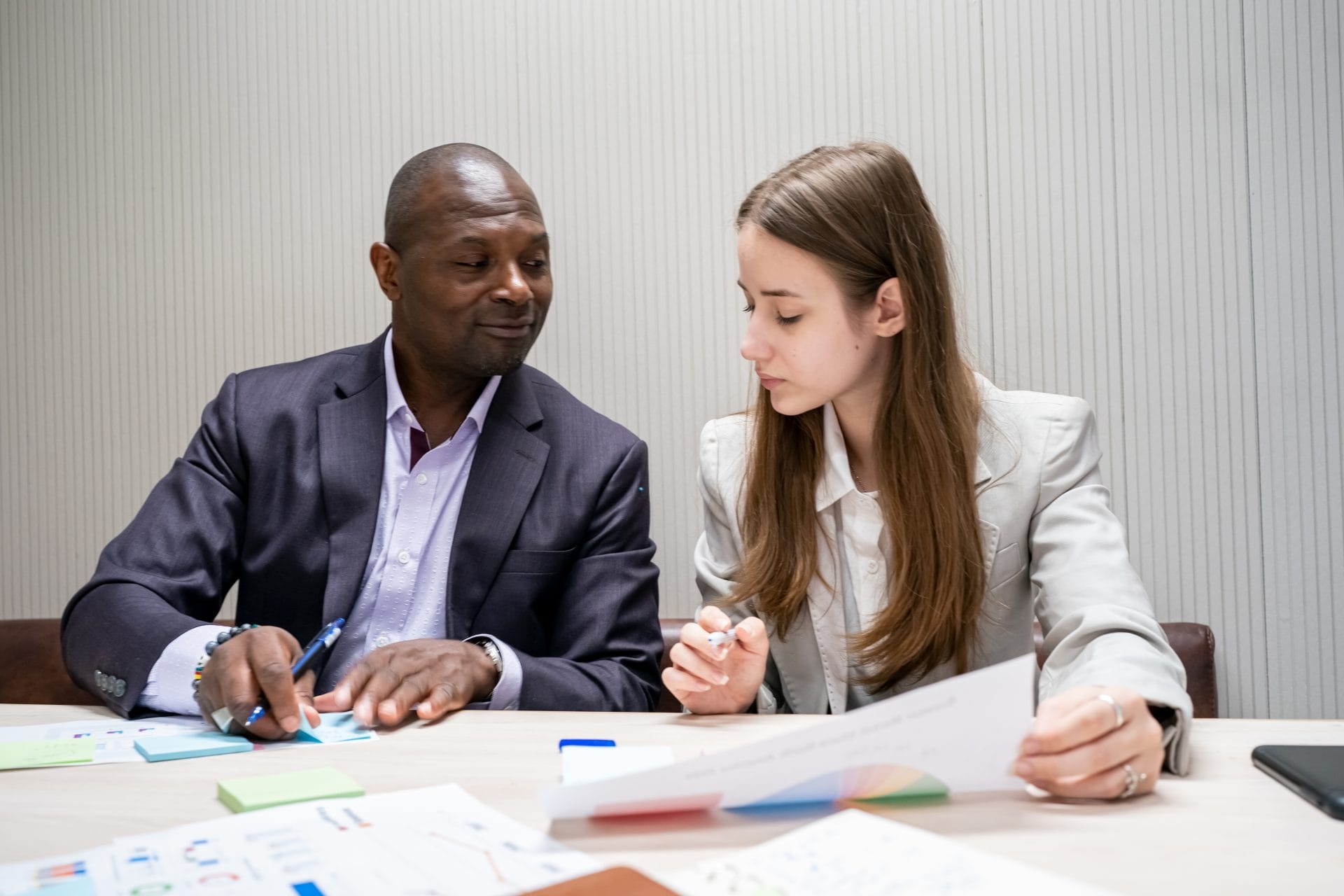 Professional mentor guiding a young adult during a meeting, representing structured learning and workplace support.