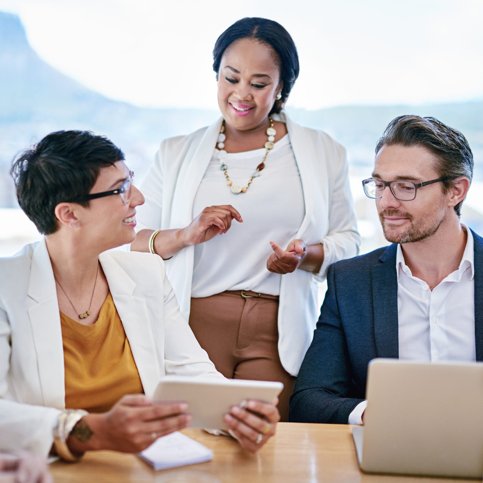 Three professionals in discussion at a bright office table, symbolizing collaboration between business and education leaders.