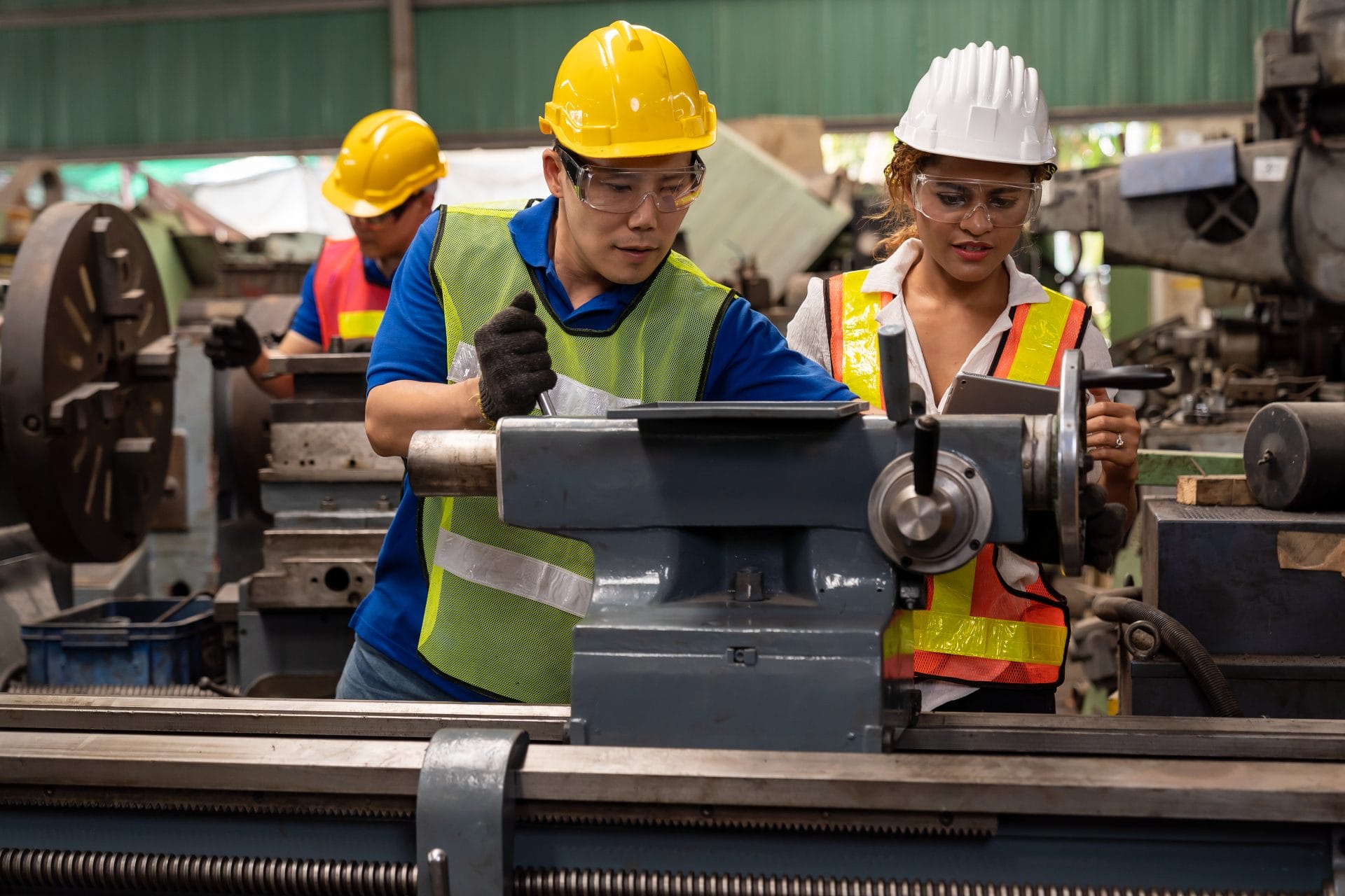 Two manufacturing employees wearing safety gear working together on machinery, representing training and workforce development.