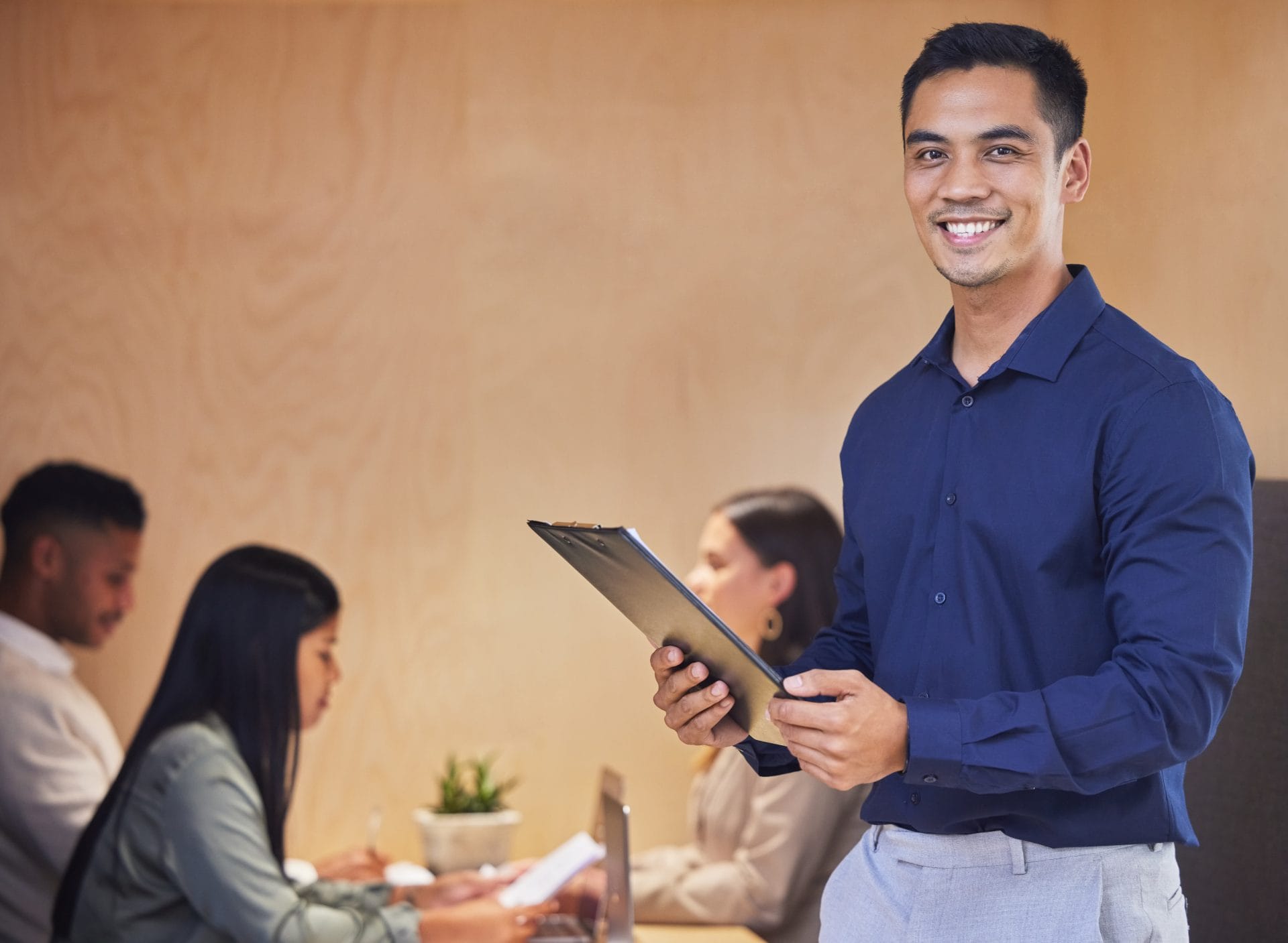 Smiling professional holding a clipboard during a meeting, representing confidence and readiness to begin a new career.