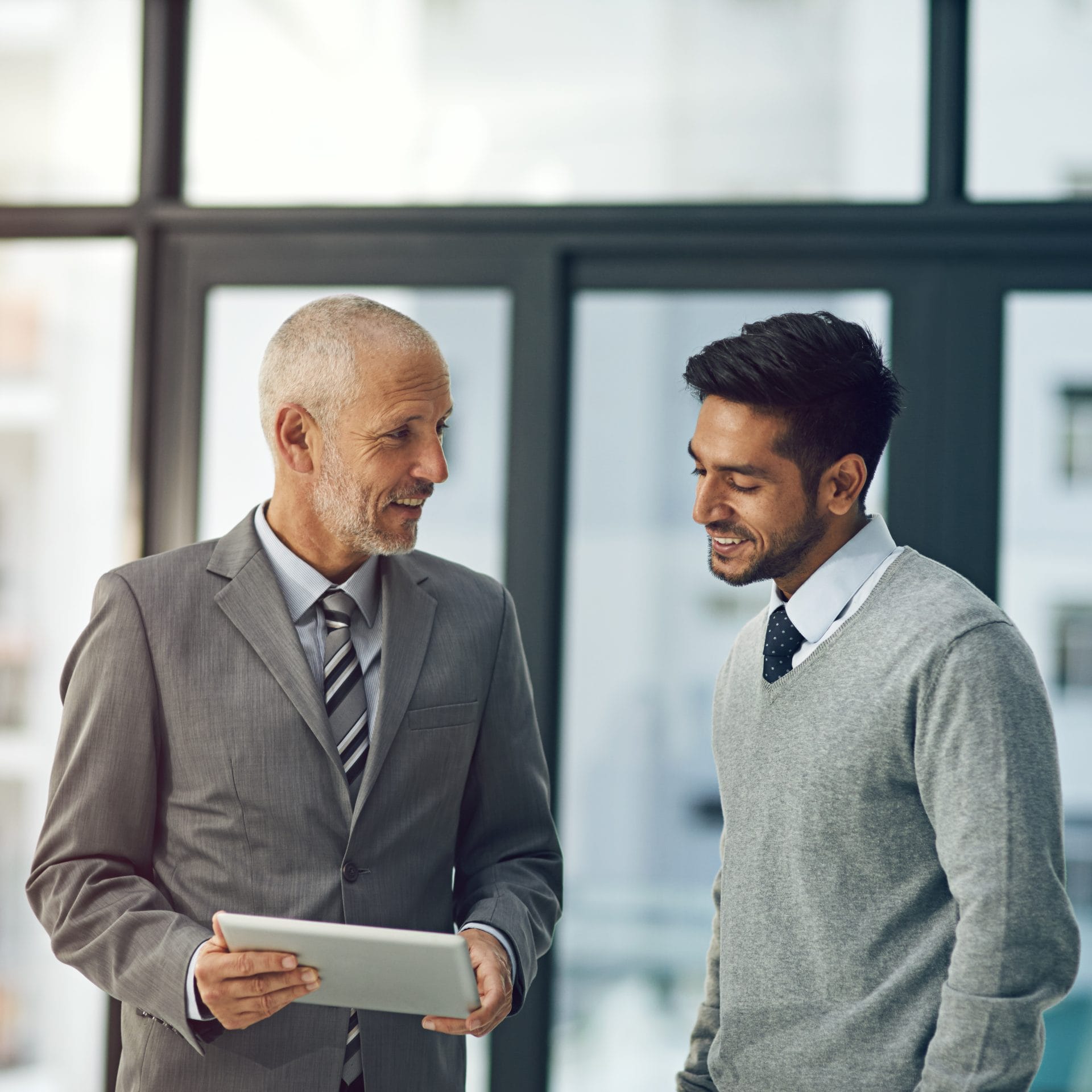Two professionals shaking hands and smiling during a meeting, symbolizing trust and collaboration in hiring.