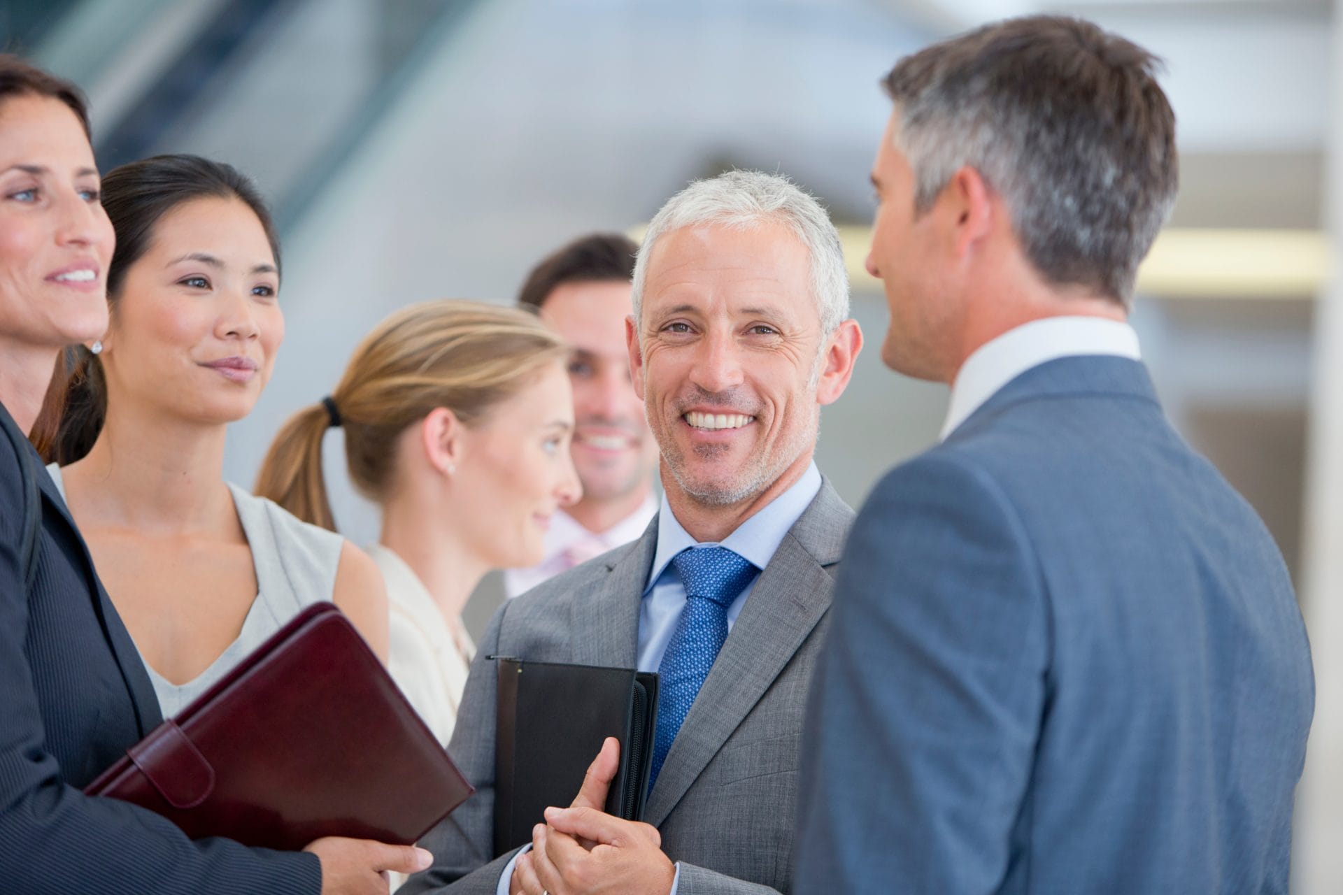 Smiling group of business professionals in conversation, representing collaboration among industry leaders.