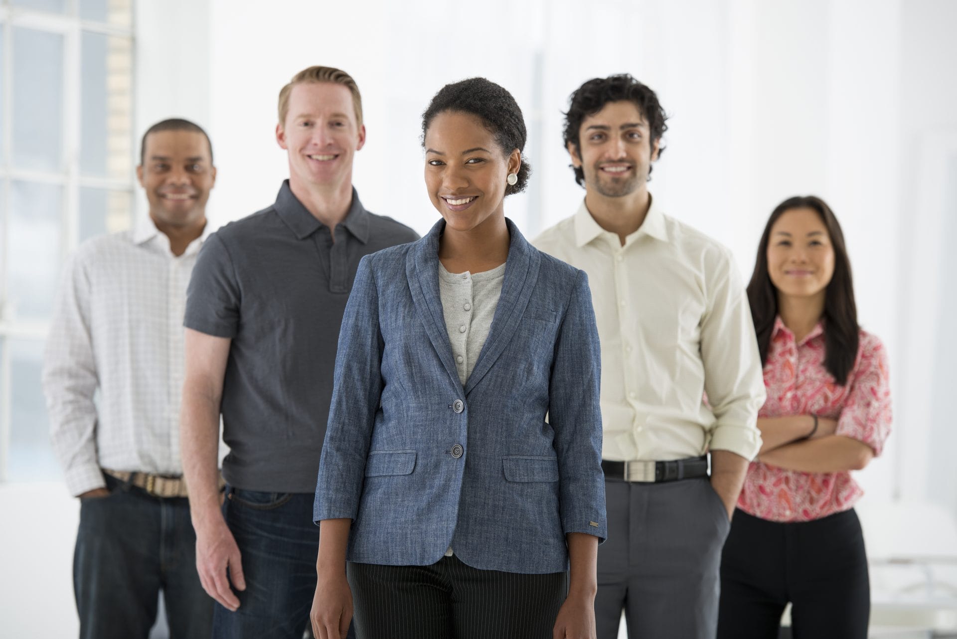 Diverse group of professionals standing together and smiling, representing teamwork and inclusivity.