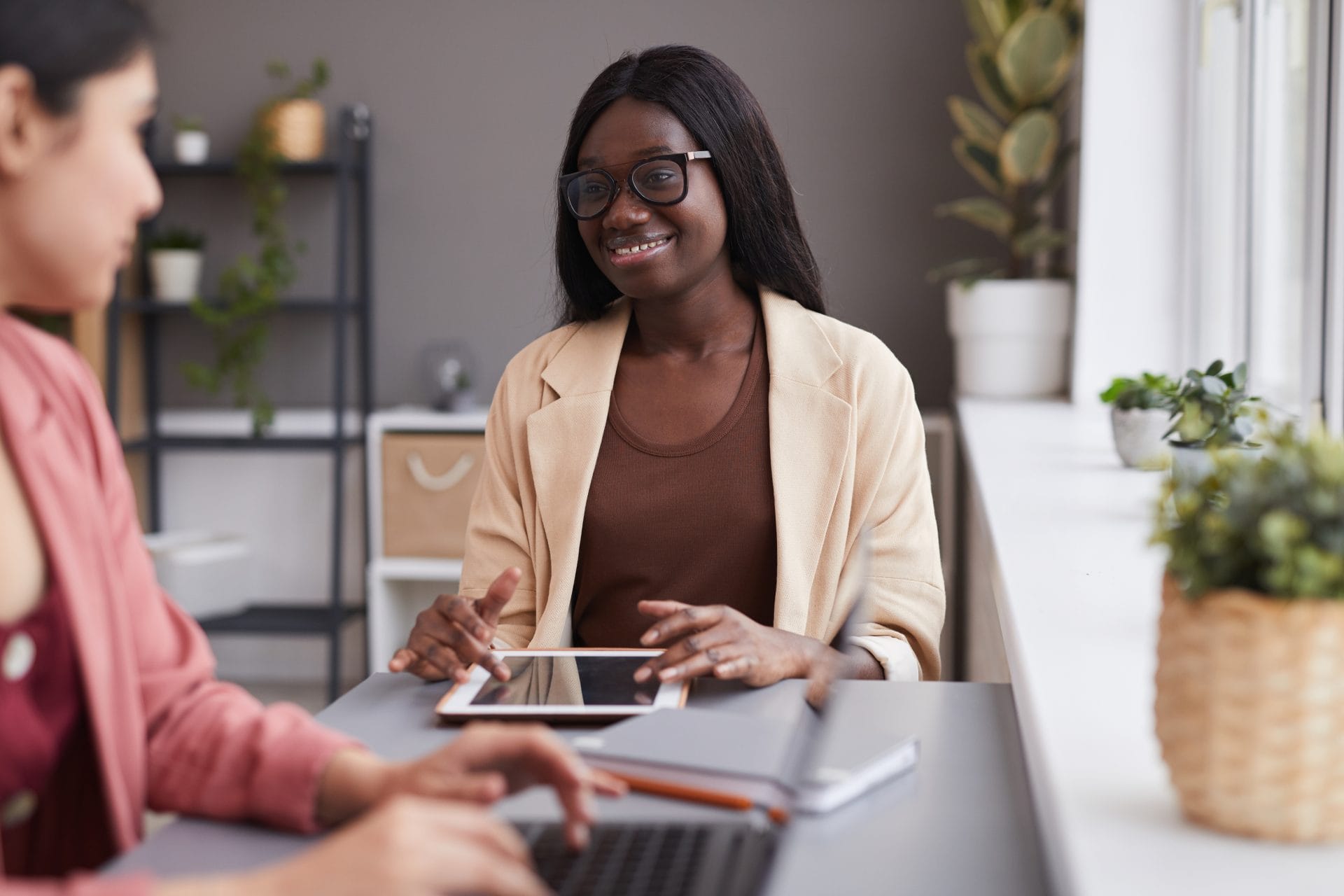 Smiling professional sitting at a desk with a tablet, representing mentorship and real-world learning opportunities.